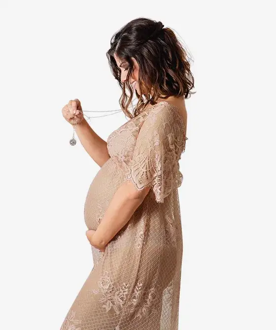 Une future maman tient la chaîne de son bola et regarde son ventre